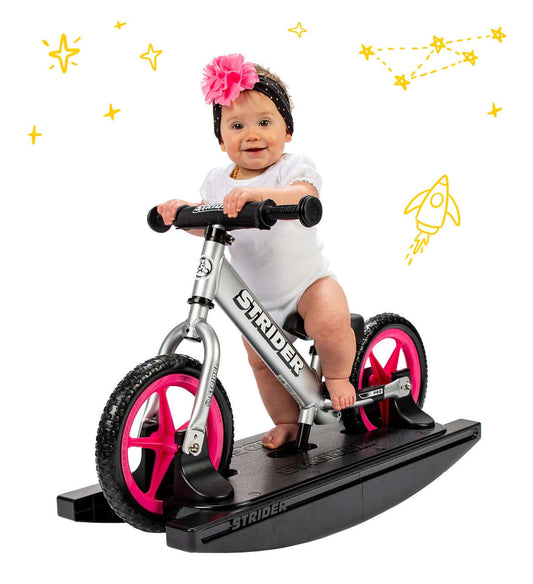 Baby on Strider Pro 2-in-1 Rocking Bike, enjoying a unique balance bike experience with pink wheels and a modern design.