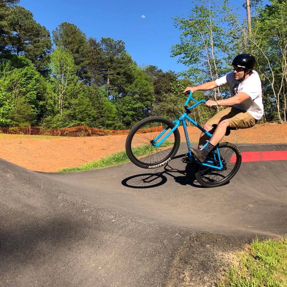 Rider performing tricks on Eastern Bike Growler LTD on a dirt track with trees in the background.