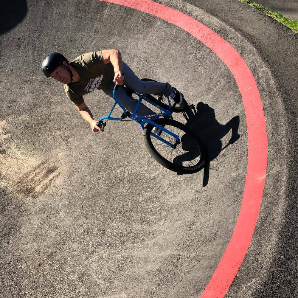 Rider performing a BMX maneuver on the Eastern Bike Growler LTD in a pump track with a curved red line.