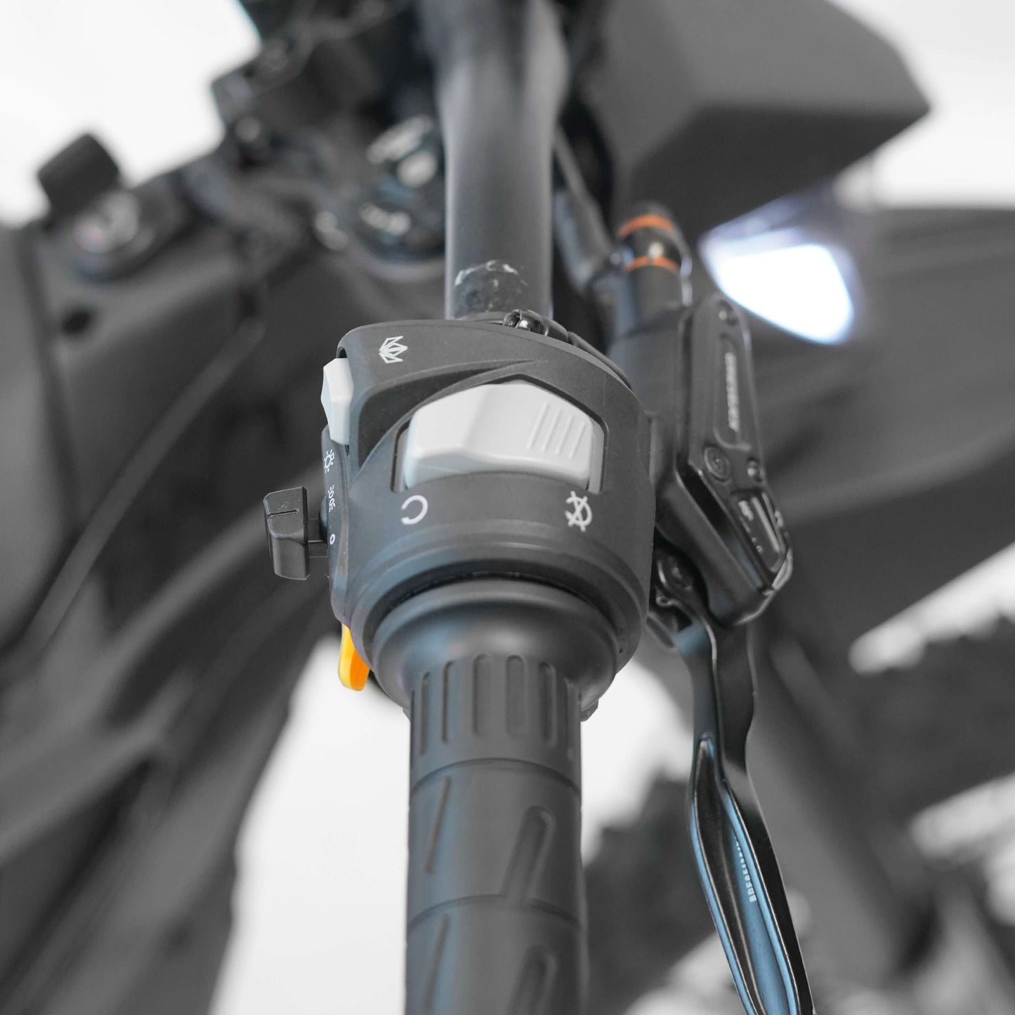 Close-up of Throne SRPNT e-DIRT BIKE handlebar controls for speed and lighting adjustment.