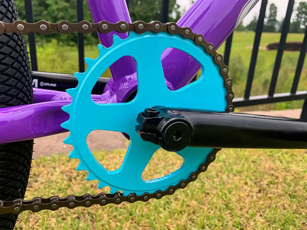 Close-up of Eastern Bike Big Reaper LTD's anodized blue sprocket and crankset on a purple frame.