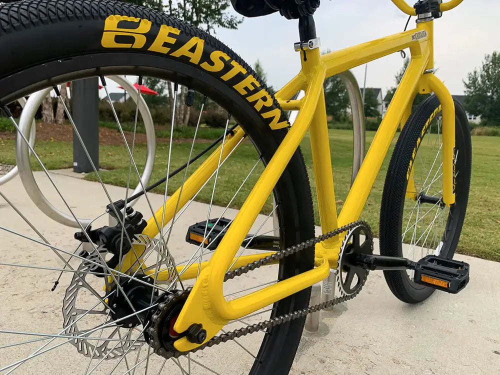 Close-up of Eastern Bike Big Reaper LTD in yellow, showcasing the hub, tires, and sleek design on a sunny day.