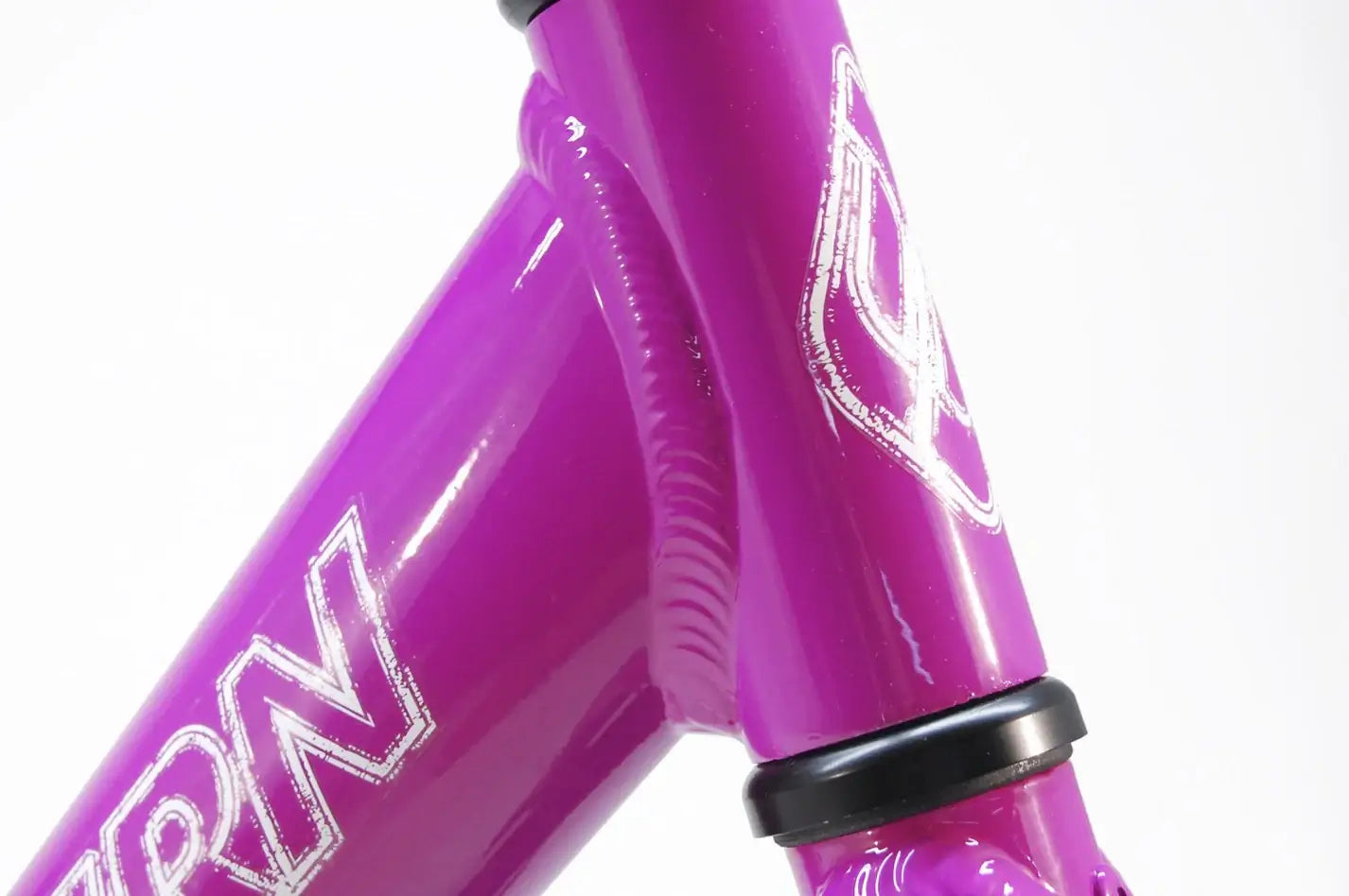 Close-up of Eastern Pusher Balance Bike's lightweight pink alloy frame and logo detail.