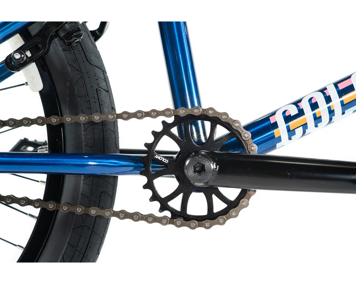 Close-up of Colony Premise BMX bike's blue frame, chain, and crankset showcasing premium build quality.