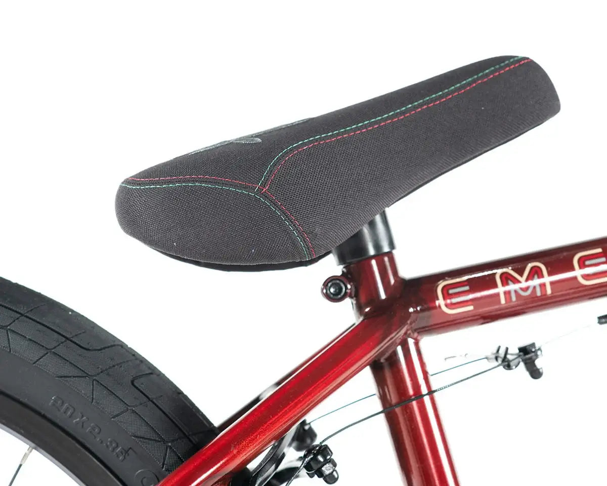 Close-up of the Colony Emerge BMX bike seat, featuring a textured black cover and red stitching for enhanced grip.