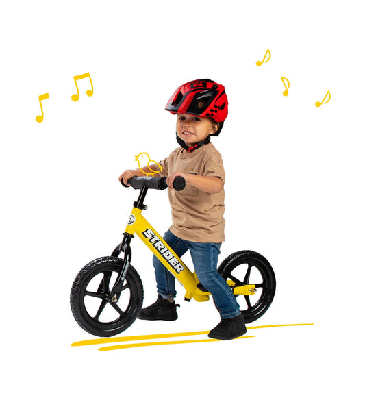 Child riding a Strider balance bike wearing a Strider 2-in-1 Full Face Helmet, showcasing safety and fun.